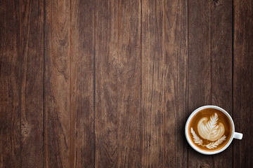 A cup of hot latte art or cappuccino coffee on wooden table. Top view