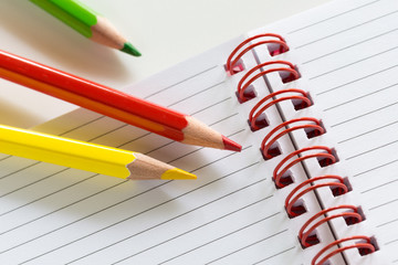 Pastello rosso, verde e giallo su notes a righe con spirale rossa