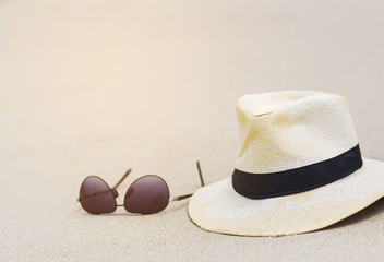 Fototapeta na wymiar Hat and sunglasses on fine sand beach in sunny day