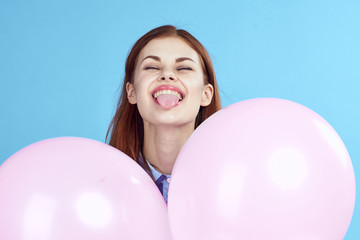 Fototapeta na wymiar woman holds pink balloons and shows tongue, portrait