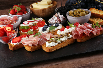 Italian antipasti wine snacks set. Cheese variety, Mediterranean olives, pickles, Prosciutto di Parma, tomatoes and wine in glasses. Spanish tapas