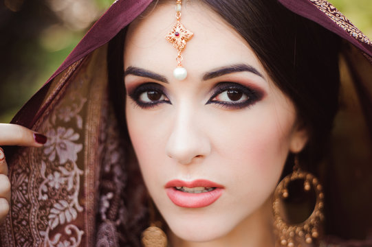 Portrait of beautiful indian girl . Young hindu woman model with tatoo mehndi and kundan jewelry.