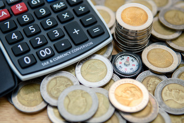 Closeup the compass with blurred coins and caculator on wooden background for financial guide, investor compass, business Growth, money saving planning concept. Selective focus - 169844213