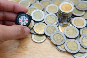 Closeup the compass in men hand and blurred coins on wooden background for financial guide, investor compass, business Growth, money saving planning concept. Selective focus - 169844252