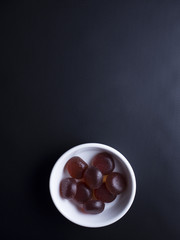 Strawberry flavoured jelly sweets from japan in small ramekin, isolated on black background