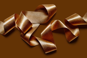 Close up of bronze metallic ribbon isolated on bronze brown background