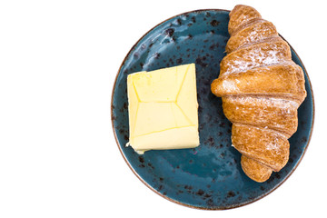 Fresh croissant with butter on blue plate on white background
