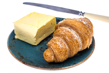 Fresh croissant with butter on blue plate on white background