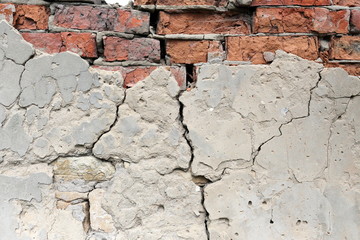 An old brick wall with cracked cement.