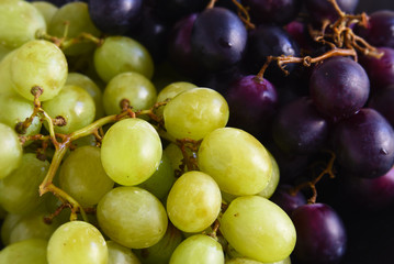 Naklejka na ściany i meble green and purple grapes as a food background, close up with selected focus and narrow depth of field