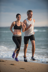 A couple wearing sportswear is running on the beach