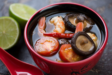 Close-up of a red bowl with hot Tom Yum soup, selective focus, horizontal shot