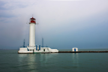 White lighthouse with a red tip in the sea.