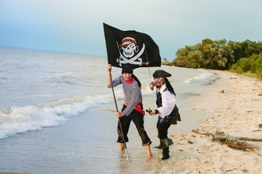 Two pirates with a flag on the seashore