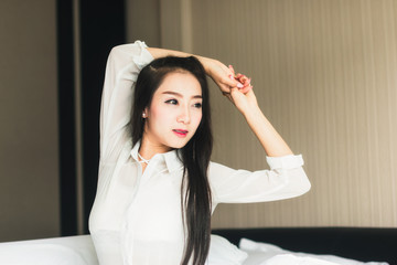 Naklejka premium Beautiful Asian woman wearing white dress looking good Relax in the bedroom.