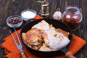Cast-iron frying pan with marinated chicken thighs for frying