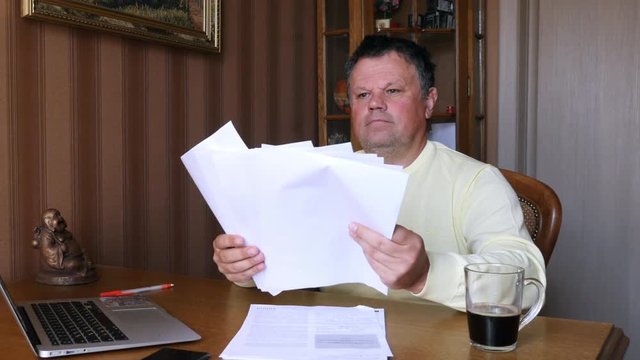 Angry businessman scatters documents.
