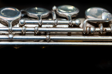 Obraz premium symphonic music concept - closeup on western concert flute body lies on the pure black surface, middle section with keys of the instrument, studing and orchestra concerts usage, macro