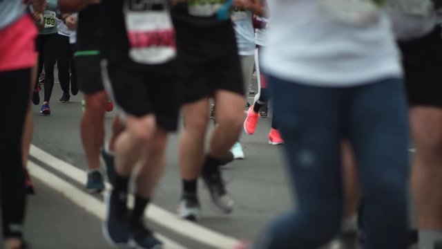 Close-up view of the people s feet in sportswear and sneakers running the marathon of a long distance at city festival.