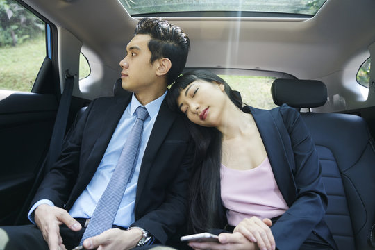 Tired Business Couple Resting In The Back Seat Of A Car