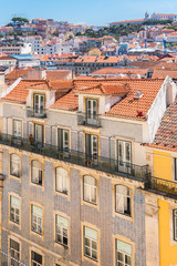 Fototapeta premium Orange tiles roofs in lisbon, Portugal, typical houses, woman on a balcony 