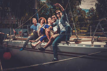 Obraz na płótnie Canvas Happy friends taking selfie on a yacht
