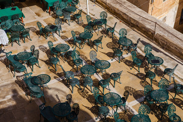 Cafe tables and chairs. View from the top. Rhythmes of Mediterranean island.