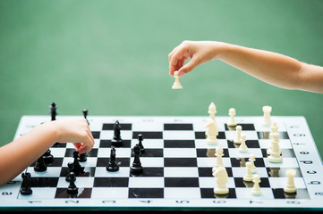 A boy and a girl are playing at a chess table