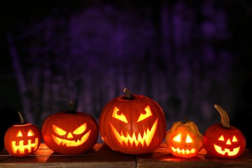 Group of Halloween Jack o Lanterns at night against a spooky forest background