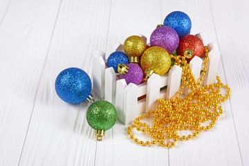 White box with colored Christmas tree balls and golden beads for decoration