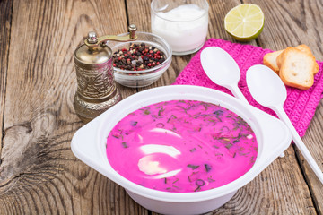 Rural dinner-beetroot soup with sour cream on wooden table