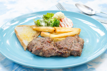 Grilled steak with french fries and vegetables and toast