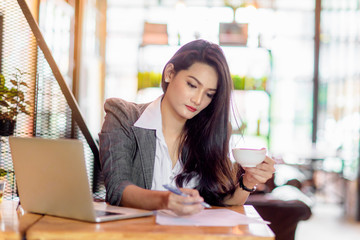 Young female freelancer working on marketing plan at coffee shop. Business concept.