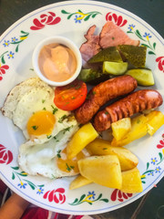 Breakfast with bacon, potato, tomato and fried eggs
