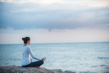 Fototapeta premium Beautiful woman practicing yoga on the beach at sunrise