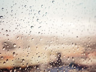 Rain in city, water drops on wet window glass, sunset