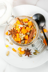 Healthy vegan food. Dietary breakfast or snack. Pumpkin pie overnight oats, with  pumpkin, yogurt, cinnamon, spices. In a glass, on a white marble table. Copy space top view