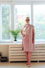 Beautiful young girl with glasses in a pink dress at the window