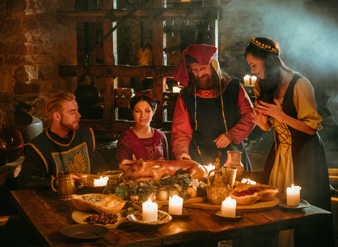 Medieval people eat and drink in castle tavern.