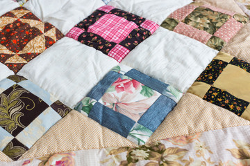 hobby, quilt, art concept. close up on piece quilt blanket patterned by a scattering of different geometrical figures such as triangles, squares and rhombuses