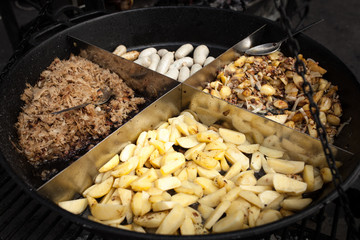 Roasted potatoes cooked outdoors in big metal cauldron pot. Street fast food