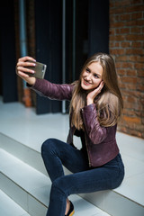 Fototapeta premium Young pretty woman taking selfie with mobile phone while sitting on stairs in city street