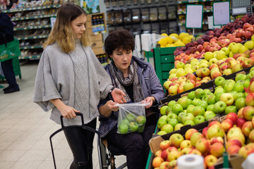 Girl helping disabled mothter in a grocery store.