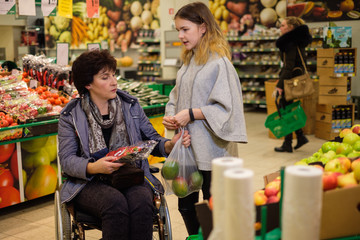 Girl helping disabled mothter in a grocery store.