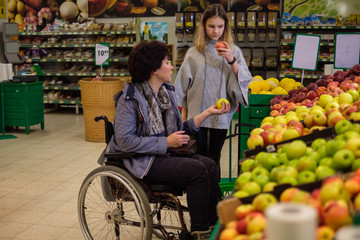 Girl helping disabled mothter in a grocery store.