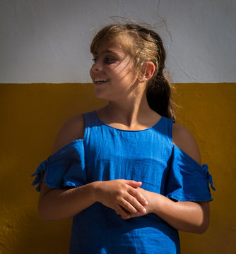 Ni&ntilde;a de 9 a&ntilde;os con vestido azul contra muro
