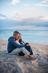 Beautiful couple sitting at the beach watching the sunset