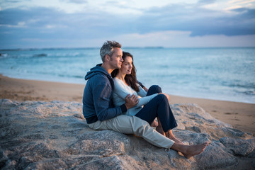 Fototapeta premium Beautiful couple sitting at the beach watching the sunset