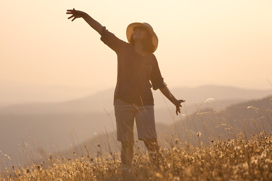 Girl posing on mountain and having fun on idyllic field at sunset