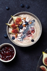 Blueberry banana smoothie bowl with figs and coconut. Dark food phorography concept. Flatlay with copy space. Vertical composition